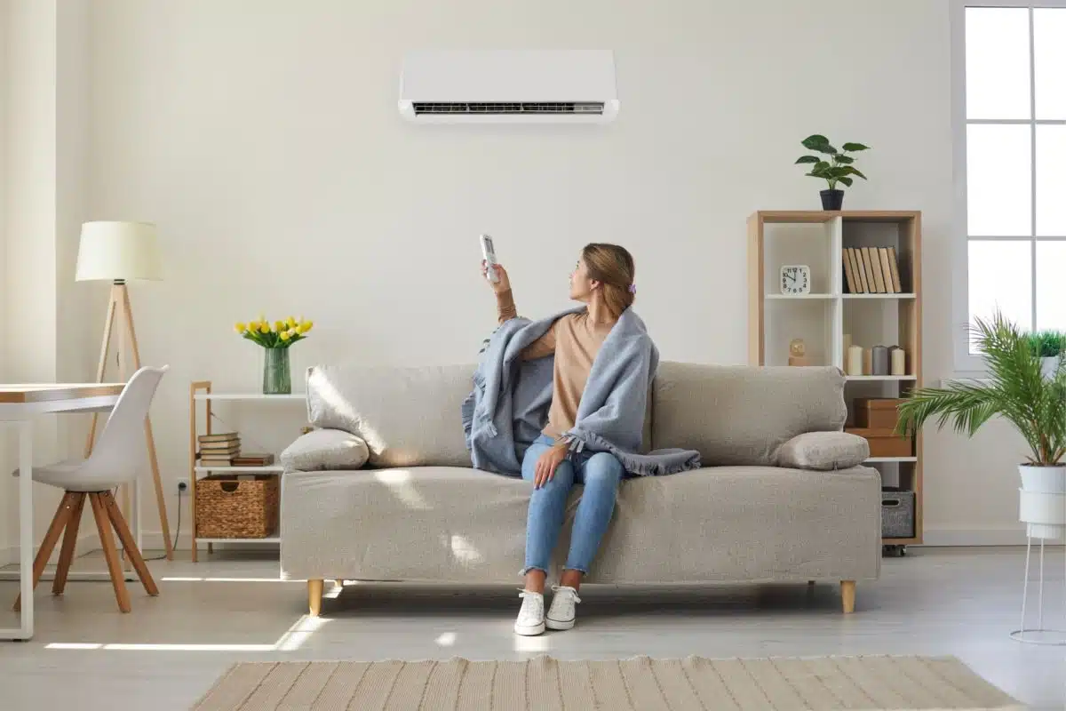 Woman adjusting air conditioner temperature